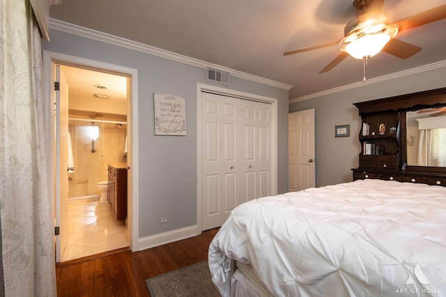 bedroom featuring crown molding, ensuite bath, ceiling fan, dark hardwood / wood-style floors, and a closet