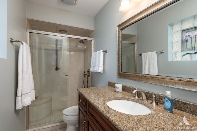 bathroom with vanity, a shower with shower door, and toilet