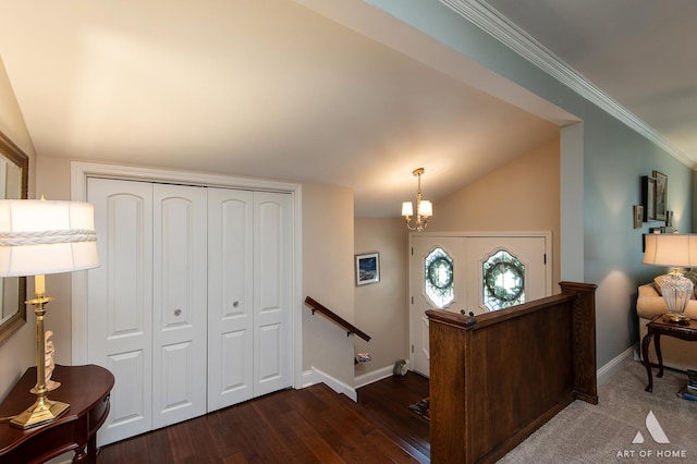 foyer entrance featuring an inviting chandelier, lofted ceiling, dark hardwood / wood-style floors, and crown molding