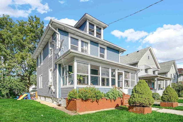 view of front of property featuring a playground, a sunroom, and a front lawn