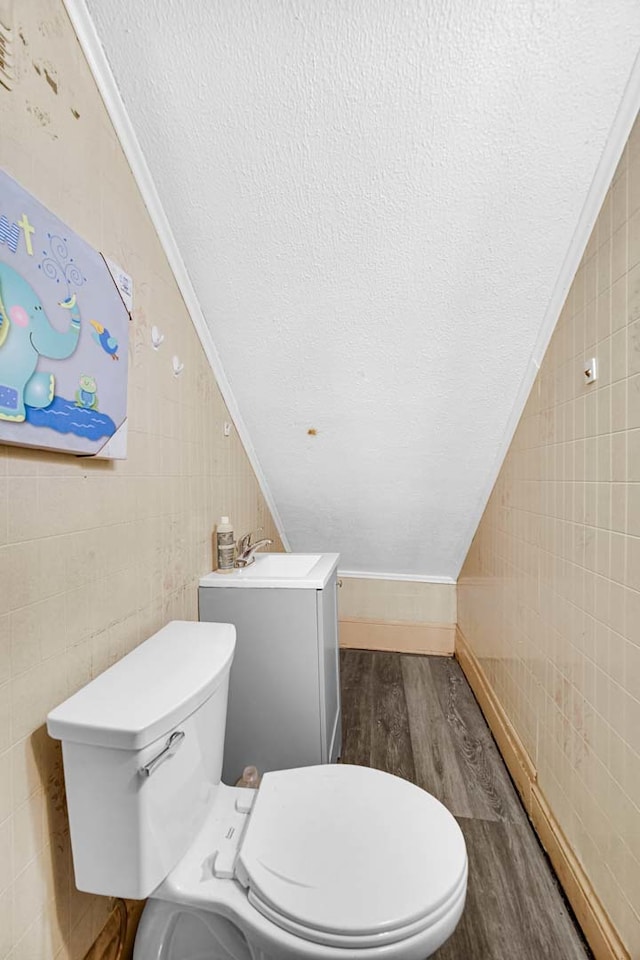 bathroom with tile walls, toilet, hardwood / wood-style flooring, and a textured ceiling