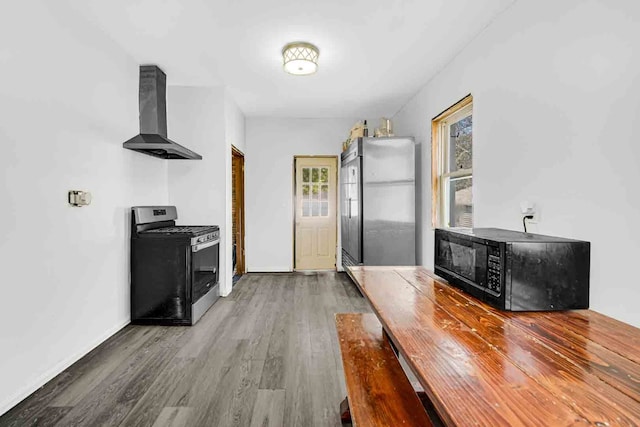 interior space featuring wall chimney range hood, hardwood / wood-style flooring, and stainless steel appliances