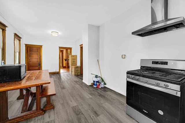 kitchen featuring wall chimney range hood, hardwood / wood-style floors, and gas range