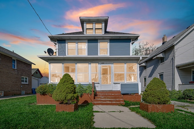 view of front of home featuring a yard and a sunroom