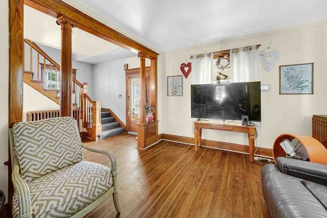 living room with plenty of natural light, radiator heating unit, wood-type flooring, and ornate columns