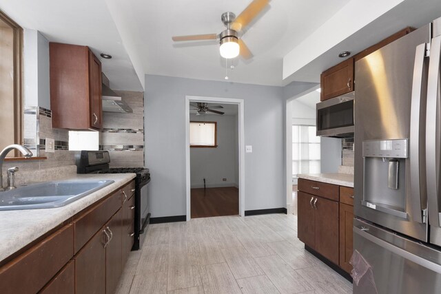 kitchen featuring tasteful backsplash, light hardwood / wood-style flooring, stainless steel appliances, sink, and ceiling fan