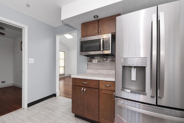 kitchen featuring vaulted ceiling, stainless steel appliances, decorative backsplash, and light hardwood / wood-style floors