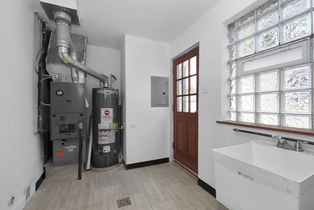 utility room featuring gas water heater, electric panel, and sink