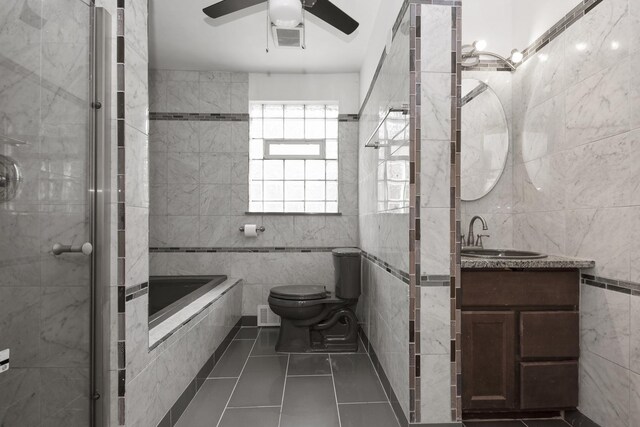 full bathroom featuring tile patterned floors, toilet, tile walls, ceiling fan, and vanity