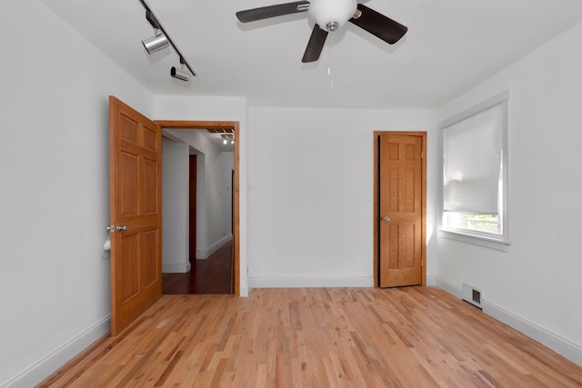 unfurnished bedroom featuring rail lighting, ceiling fan, and light hardwood / wood-style flooring