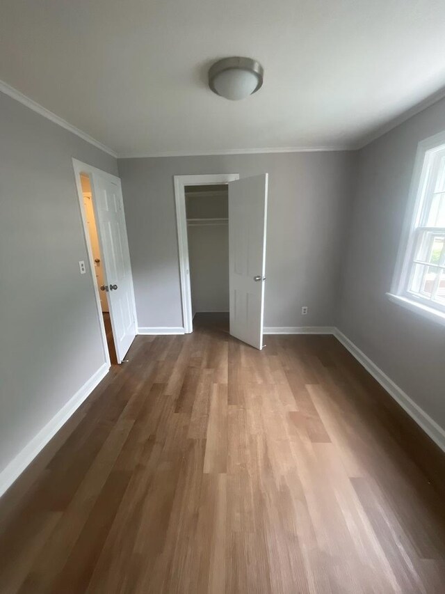 unfurnished bedroom featuring crown molding and wood-type flooring