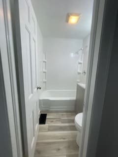 bathroom featuring wood-type flooring, bathtub / shower combination, and toilet