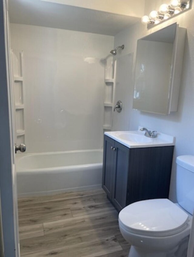 full bathroom with shower / washtub combination, wood-type flooring, toilet, and vanity