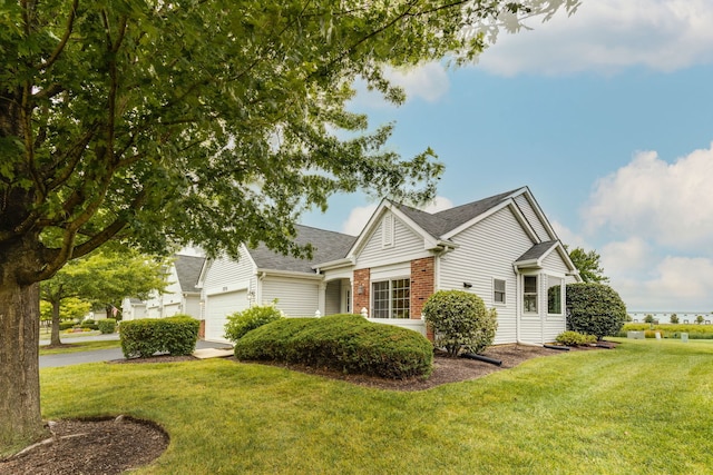 view of front facade featuring a front lawn, a garage, brick siding, and driveway