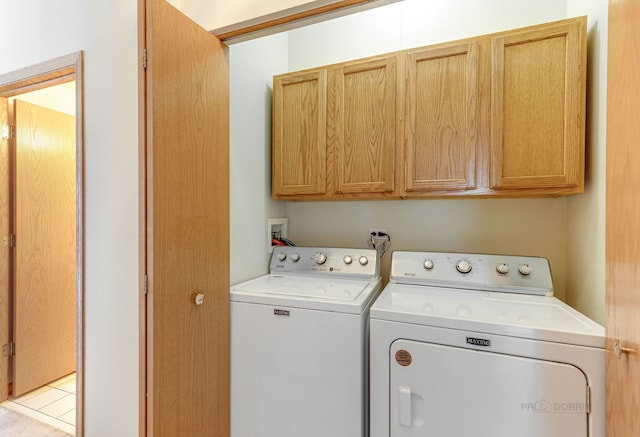 laundry area with washing machine and clothes dryer and cabinets