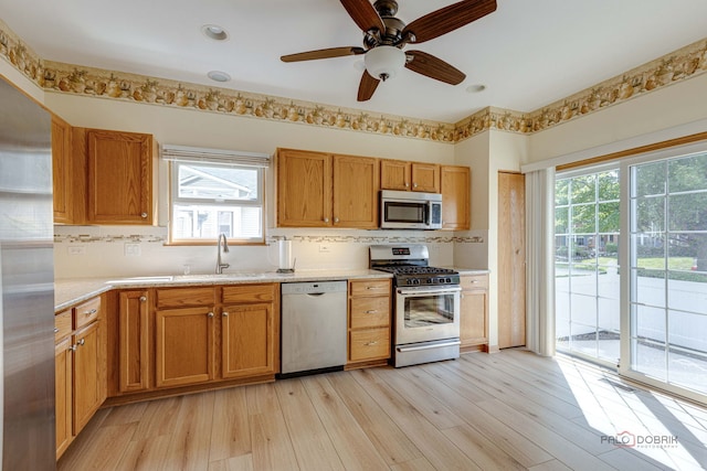 kitchen featuring tasteful backsplash, light wood-type flooring, light countertops, stainless steel appliances, and a sink