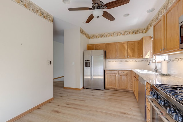 kitchen with high end appliances, light hardwood / wood-style flooring, ceiling fan, and sink