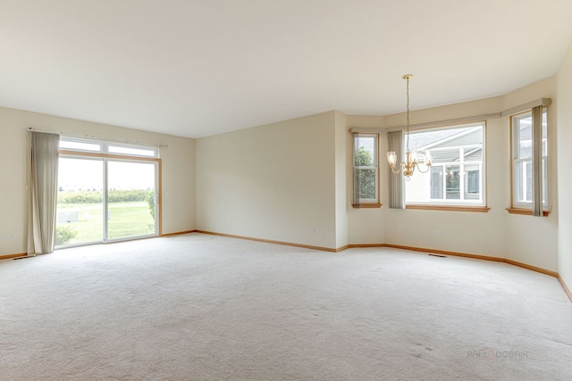 unfurnished room featuring light colored carpet, baseboards, and an inviting chandelier