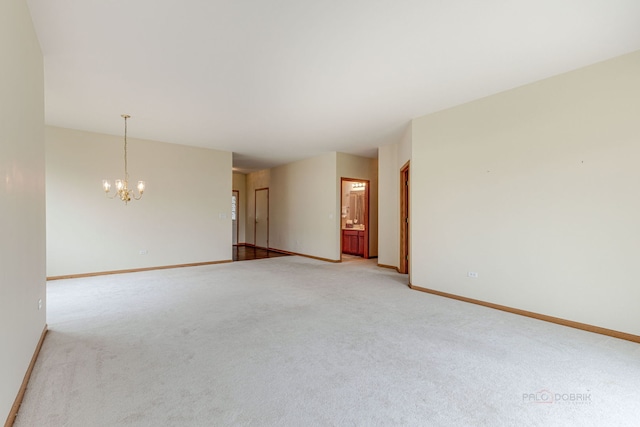 empty room with baseboards, light carpet, and a chandelier