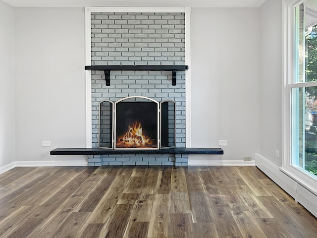 room details with hardwood / wood-style floors, baseboard heating, and a brick fireplace