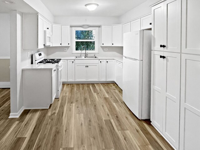 kitchen featuring white appliances, sink, white cabinets, and light hardwood / wood-style floors