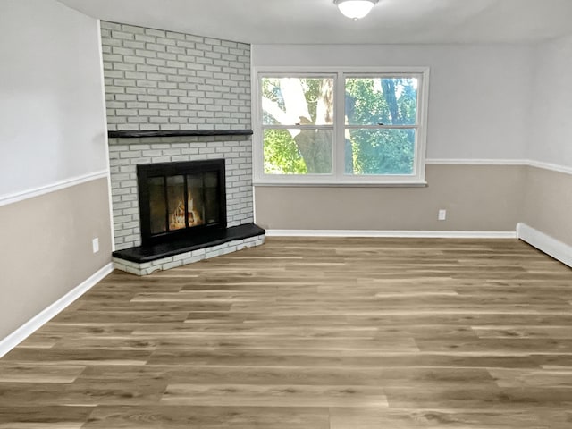 unfurnished living room with a brick fireplace and hardwood / wood-style floors