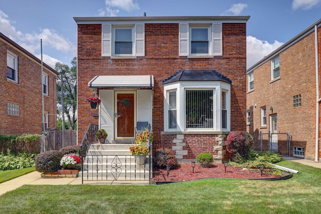 traditional-style house with a front yard, fence, and brick siding