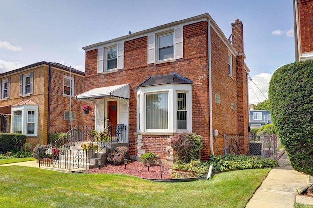 view of front of home with a front yard, a chimney, fence, and brick siding