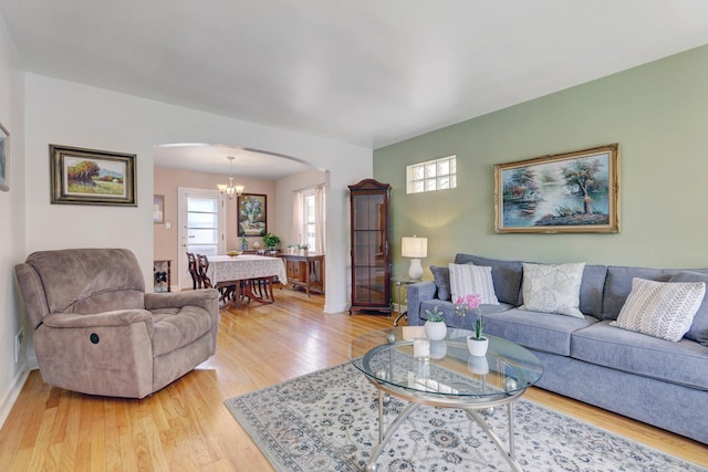 living area with arched walkways, baseboards, wood finished floors, and an inviting chandelier