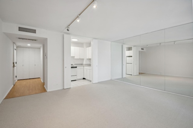 interior space with rail lighting, light colored carpet, and visible vents