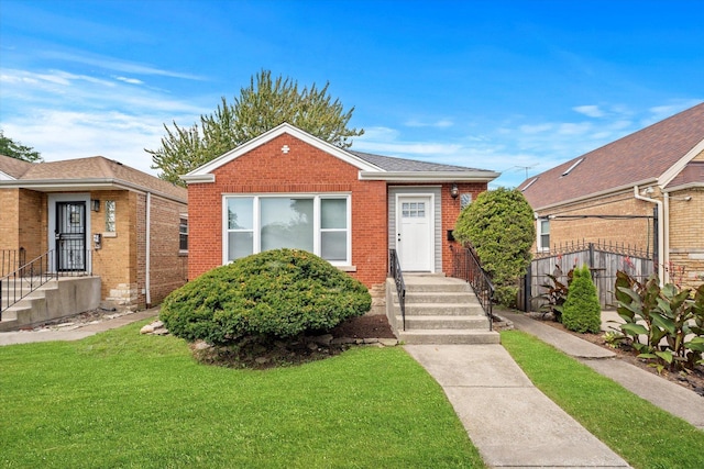 bungalow-style house with fence, a front lawn, and brick siding