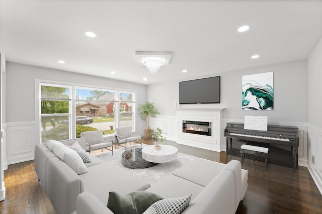 living area featuring a glass covered fireplace, dark wood-style flooring, a wainscoted wall, and recessed lighting