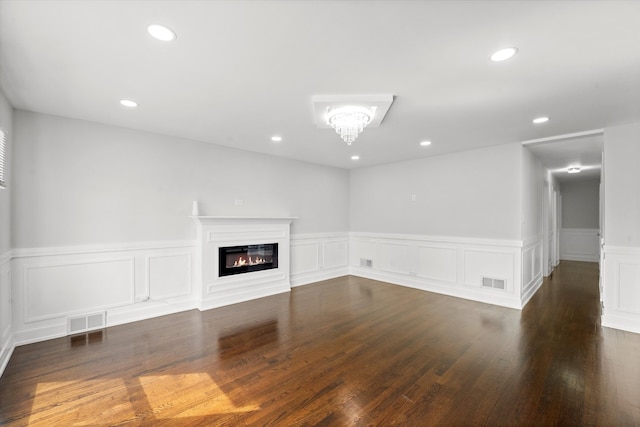 unfurnished living room featuring dark wood-type flooring and an inviting chandelier