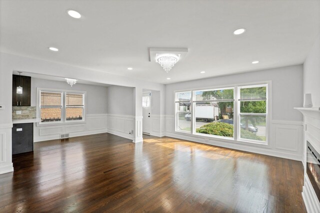 unfurnished living room with dark hardwood / wood-style floors and a notable chandelier