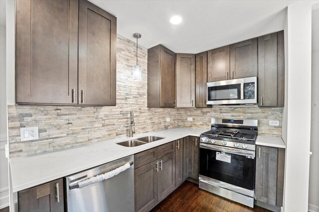 kitchen featuring dark hardwood / wood-style floors, pendant lighting, tasteful backsplash, stainless steel appliances, and sink