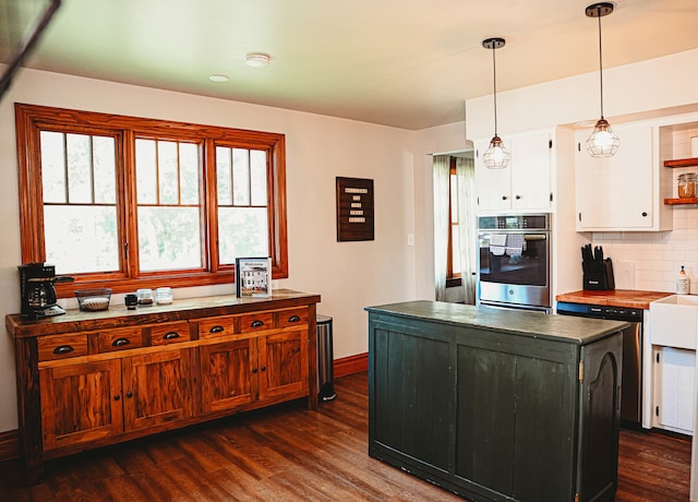 kitchen featuring decorative backsplash, dark wood-type flooring, white cabinetry, decorative light fixtures, and a center island