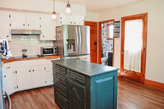 kitchen featuring backsplash, appliances with stainless steel finishes, hardwood / wood-style flooring, hanging light fixtures, and white cabinets