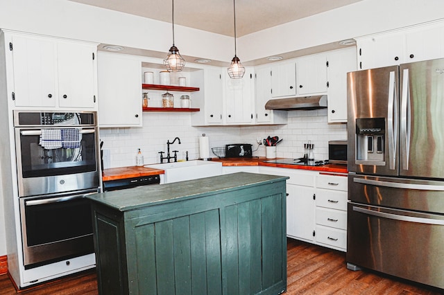 kitchen featuring appliances with stainless steel finishes, a center island, tasteful backsplash, and dark hardwood / wood-style flooring