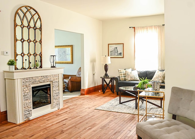 living area featuring light wood-type flooring and a tiled fireplace