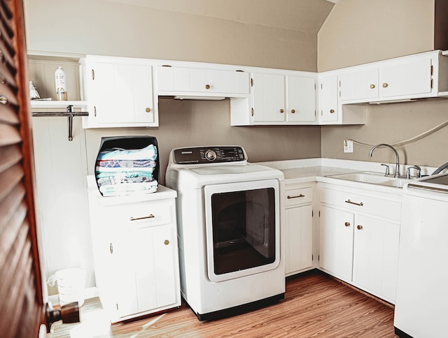 washroom featuring sink, washer and clothes dryer, cabinets, and light wood-type flooring