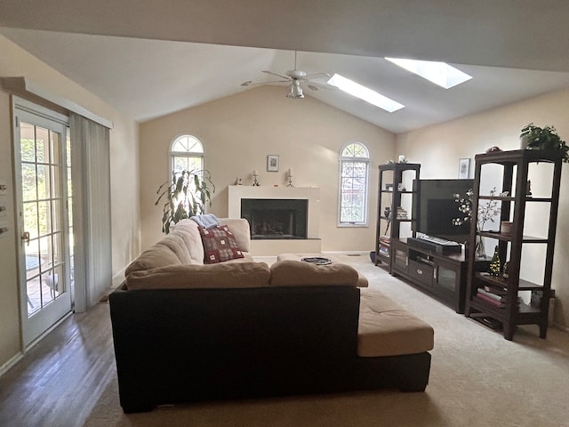 living room featuring ceiling fan, hardwood / wood-style flooring, and vaulted ceiling with skylight