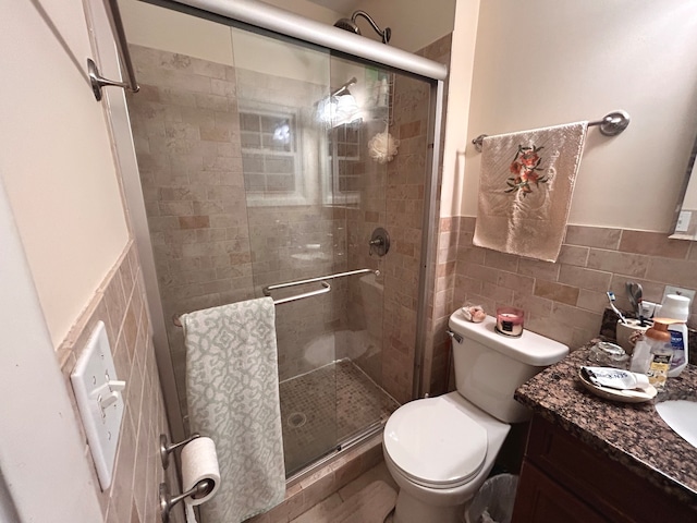 bathroom featuring tile walls, walk in shower, vanity, and toilet