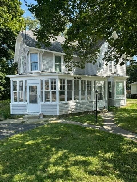 view of front of property featuring a sunroom and a front lawn