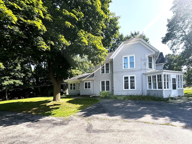 view of front facade with a front yard and a sunroom