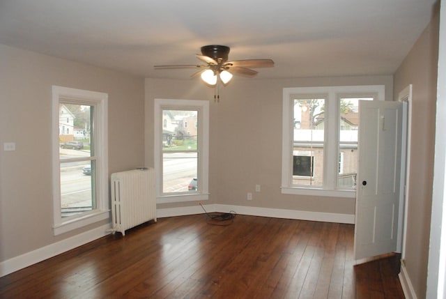 unfurnished room featuring radiator, ceiling fan, and dark hardwood / wood-style floors