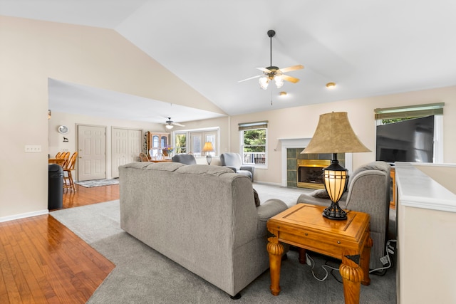 living room featuring ceiling fan, high vaulted ceiling, light hardwood / wood-style floors, and a fireplace