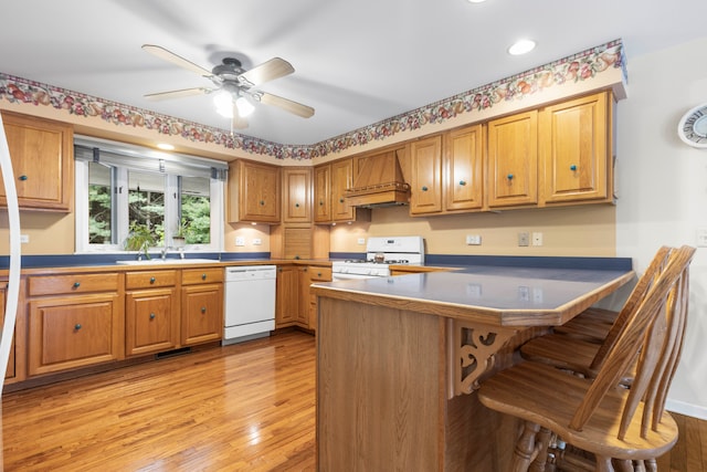 kitchen featuring light hardwood / wood-style flooring, premium range hood, a breakfast bar, kitchen peninsula, and white appliances