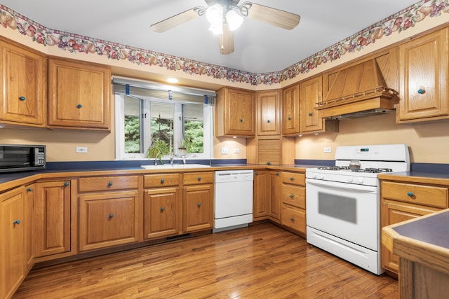 kitchen with premium range hood, sink, light wood-type flooring, white appliances, and ceiling fan