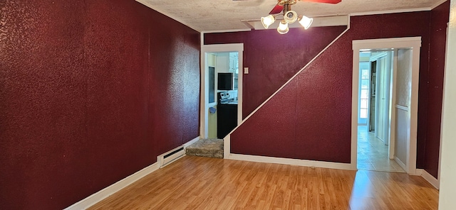 spare room with light hardwood / wood-style floors, ornamental molding, a baseboard radiator, a textured ceiling, and ceiling fan