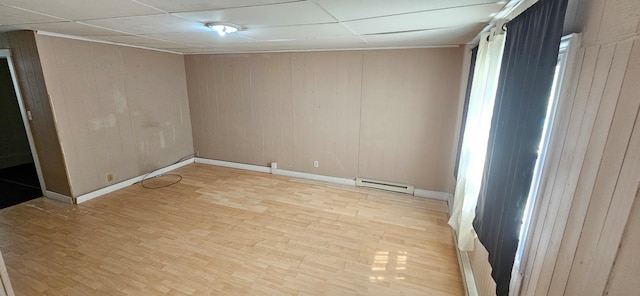 empty room with a paneled ceiling, light hardwood / wood-style floors, and a baseboard radiator